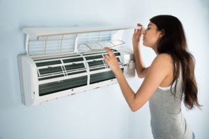 woman checking air conditioner that needs maintenance