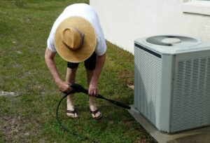 man performing ac maintenance on outside unit