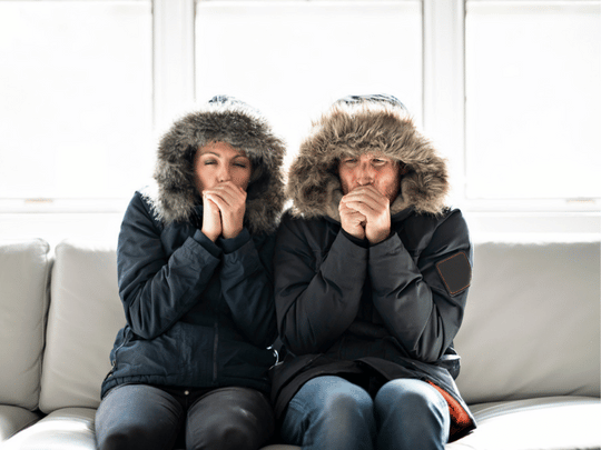 man and woman wearing winter jackets inside because furnace won't turn on
